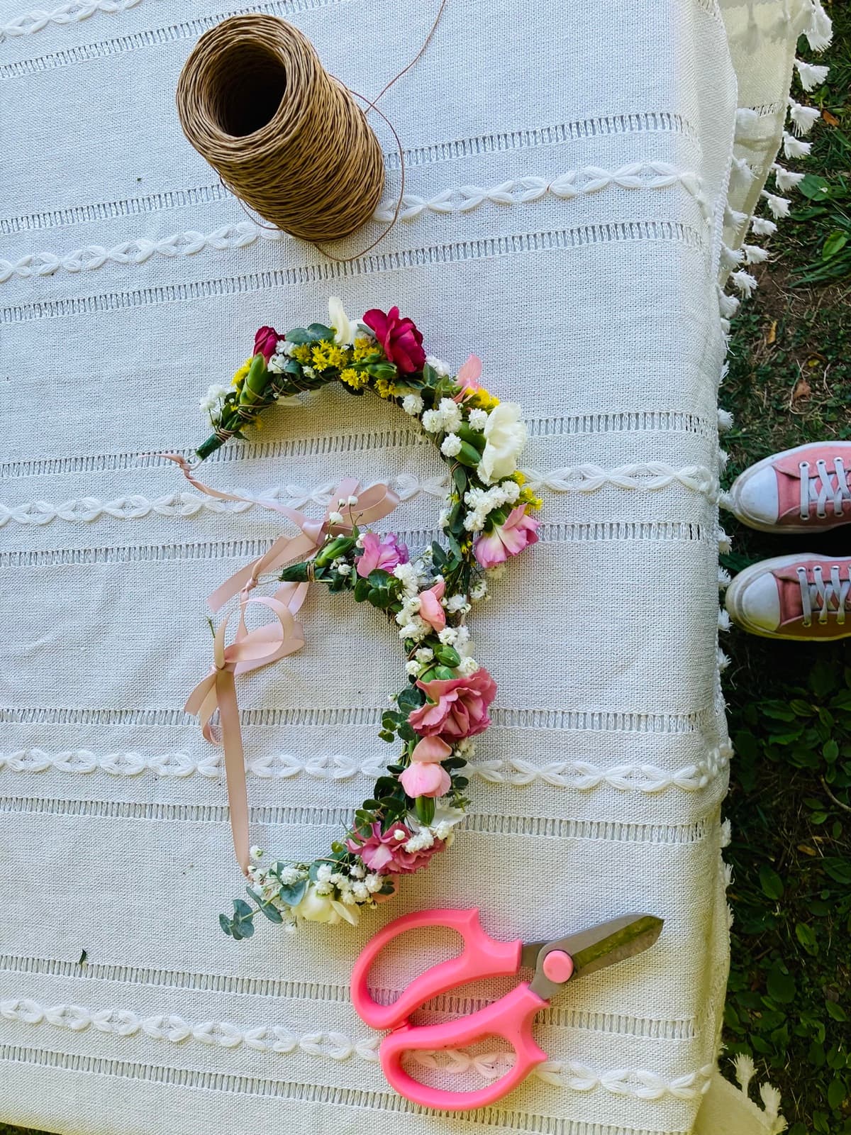 Flower crown in progress laid flat with scissors and twine — the craft of The Flower Station